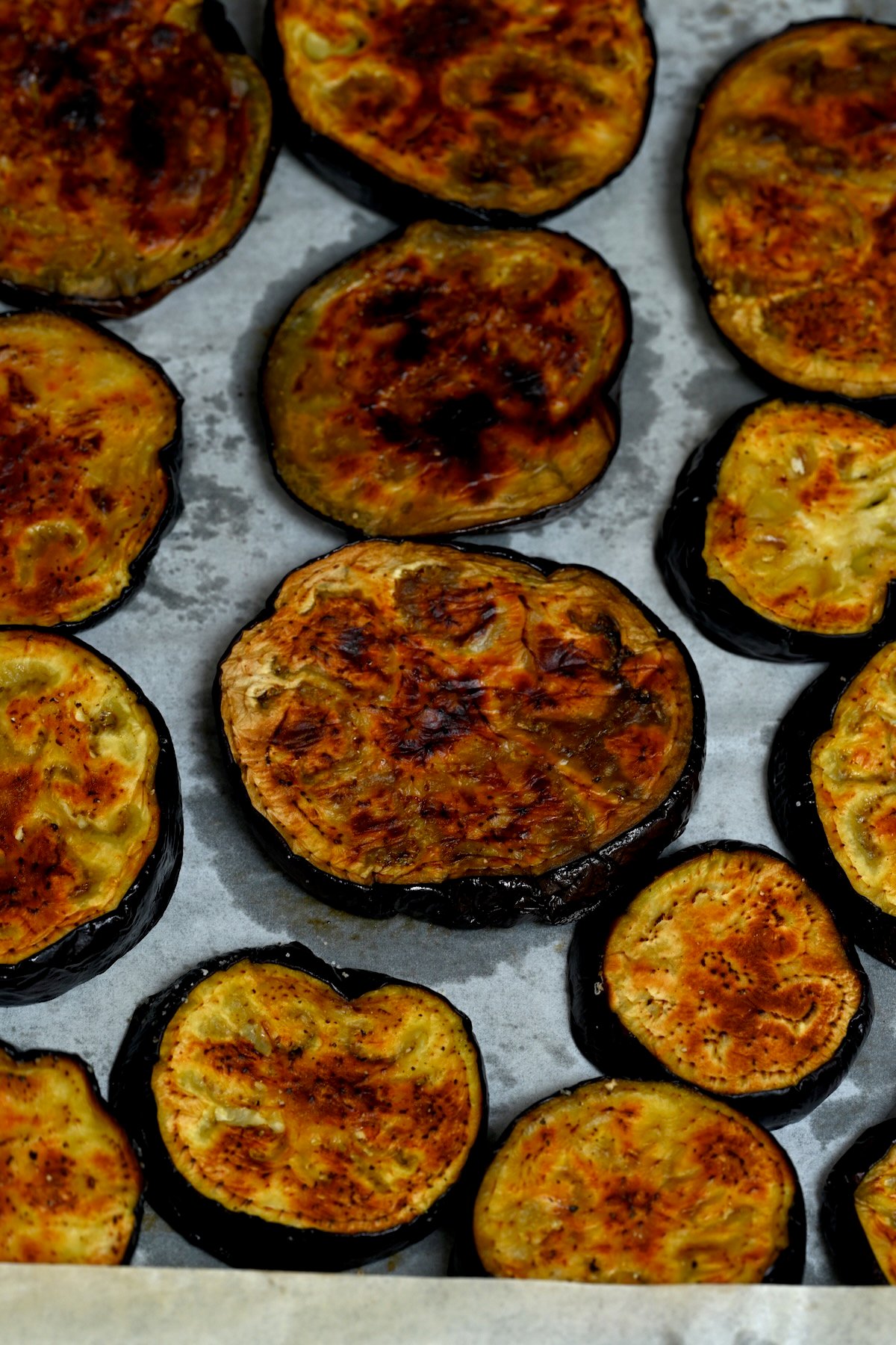 Close up of roasted eggplant slices on a baking tray