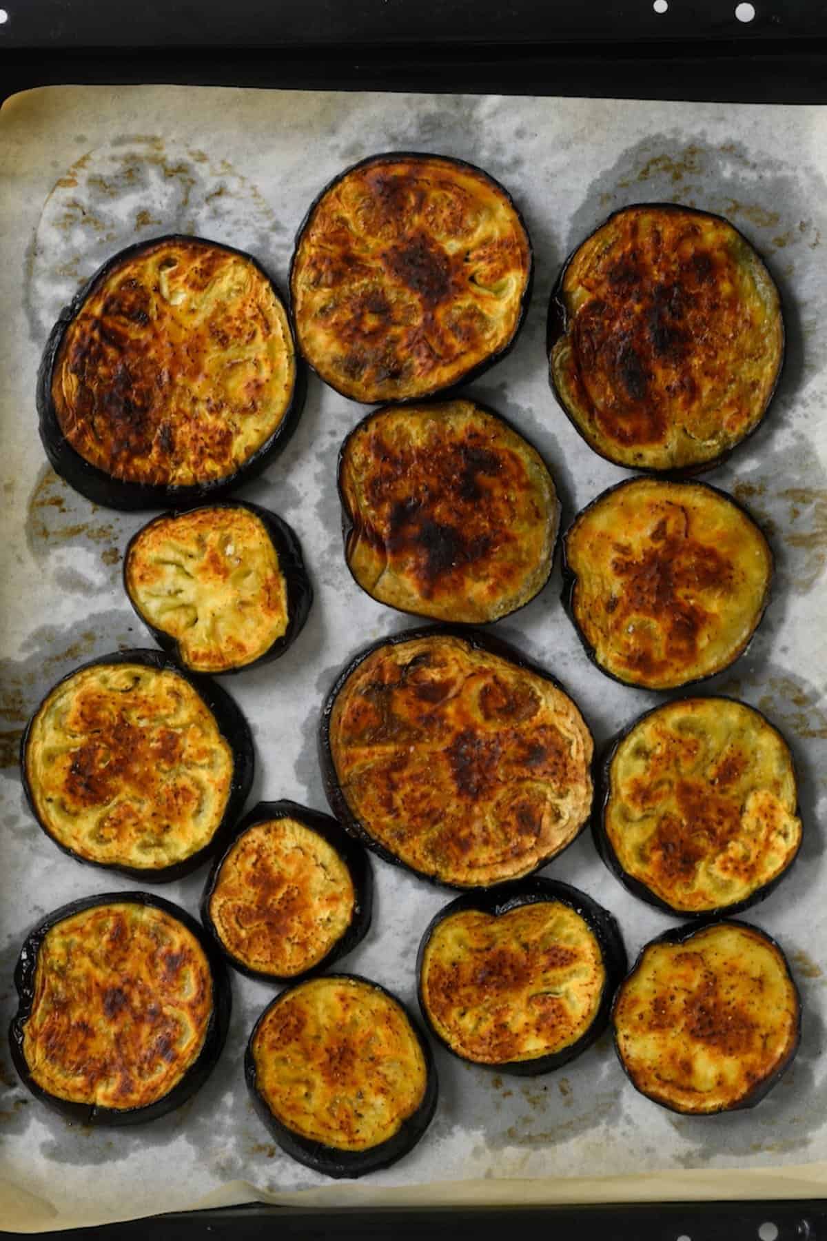 A baking tray with roasted eggplant slices fresh out of the oven