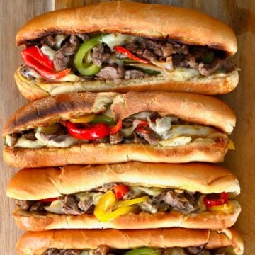 Four Philly cheesesteak sandwiches with melted cheese and peppers