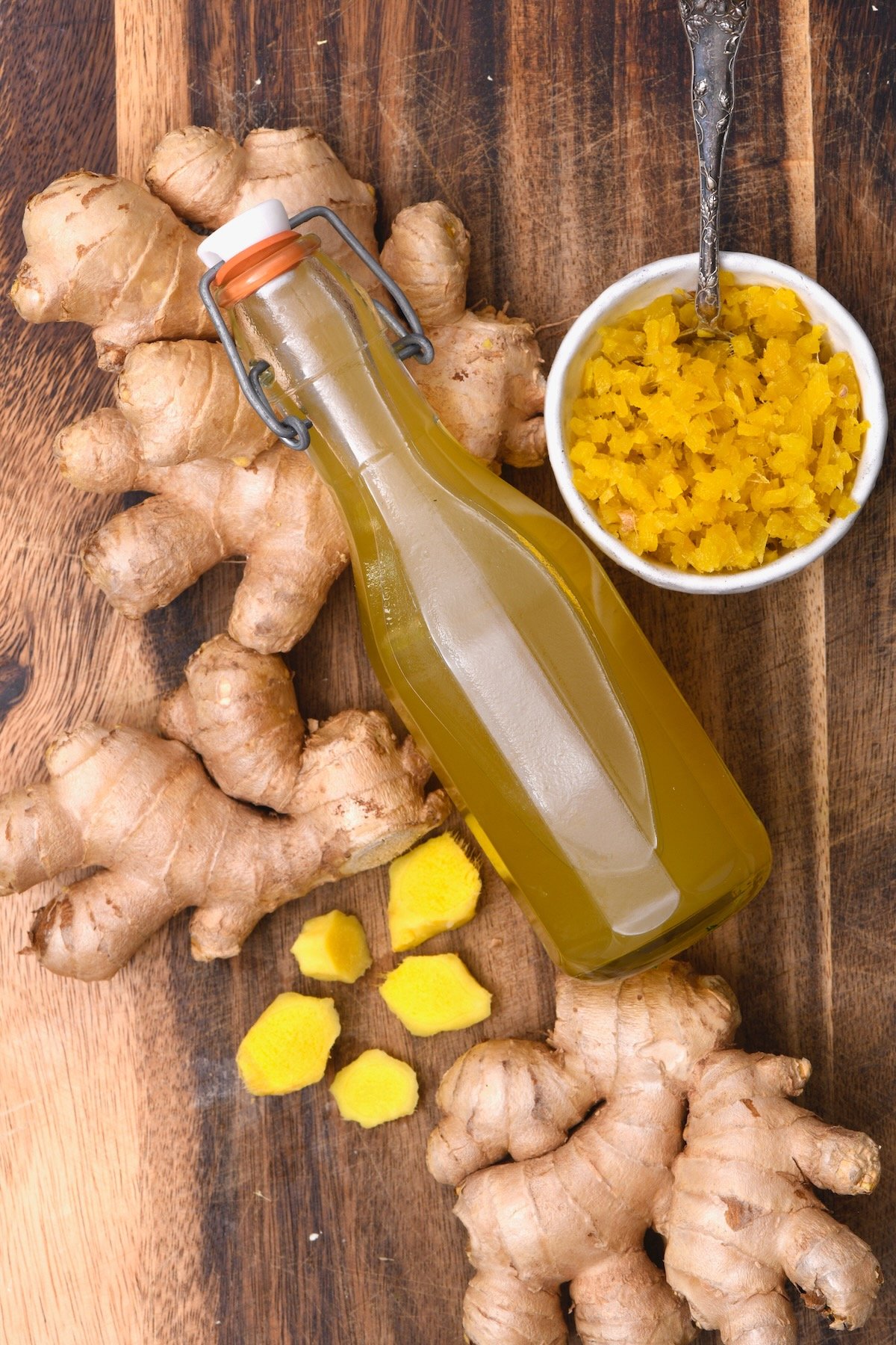 A bottle of homemade ginger syrup with ginger pulp and ginger root next to it