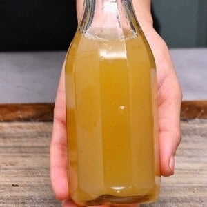 Hand holding a bottle of homemade ginger syrup