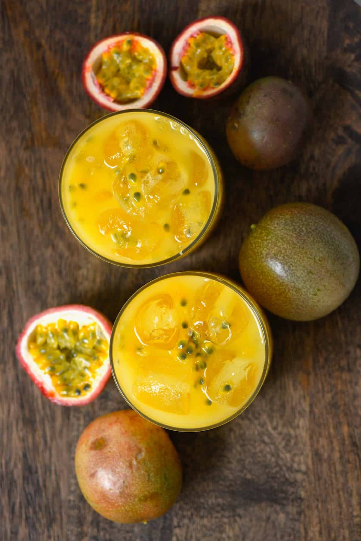 Two glasses with passion fruit and the whole fruit around them