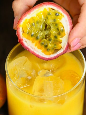 Half a passion fruit and a glass with passion fruit juice