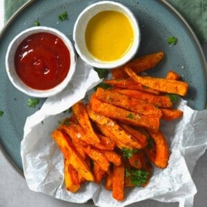 A serving of sweet potato fries served with ketchup and mustard