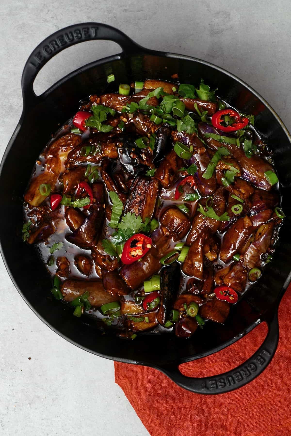 Chinese eggplant stir fry topped with red chili and cilantro
