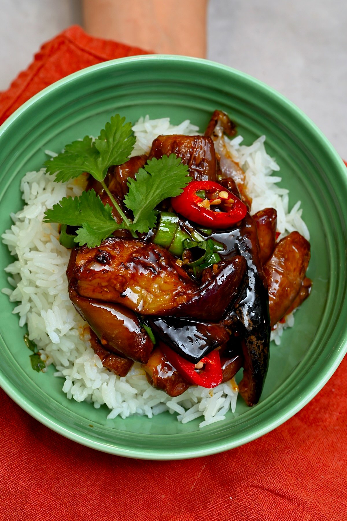 Chinese eggplant stir fry topped with red chili and cilantro over rice