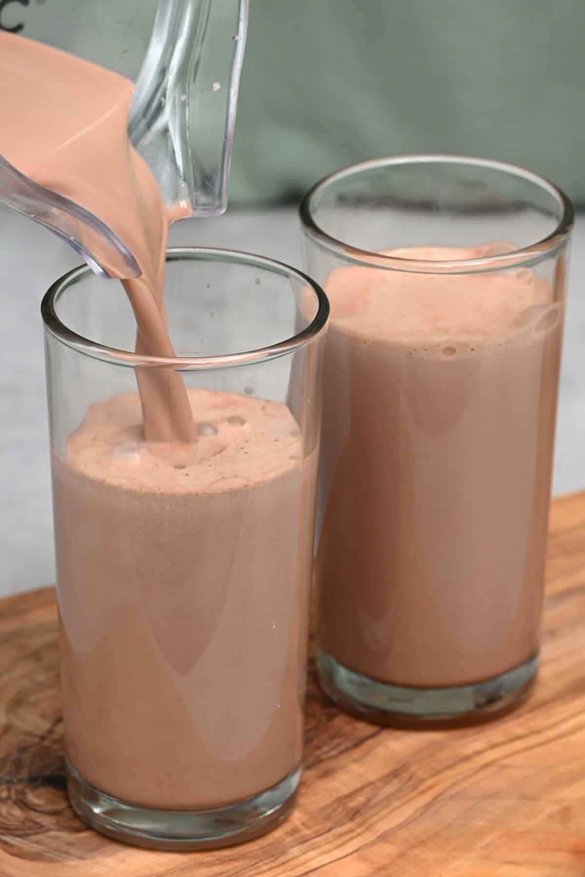 Pouring homemade milk with cacao powder into two cups