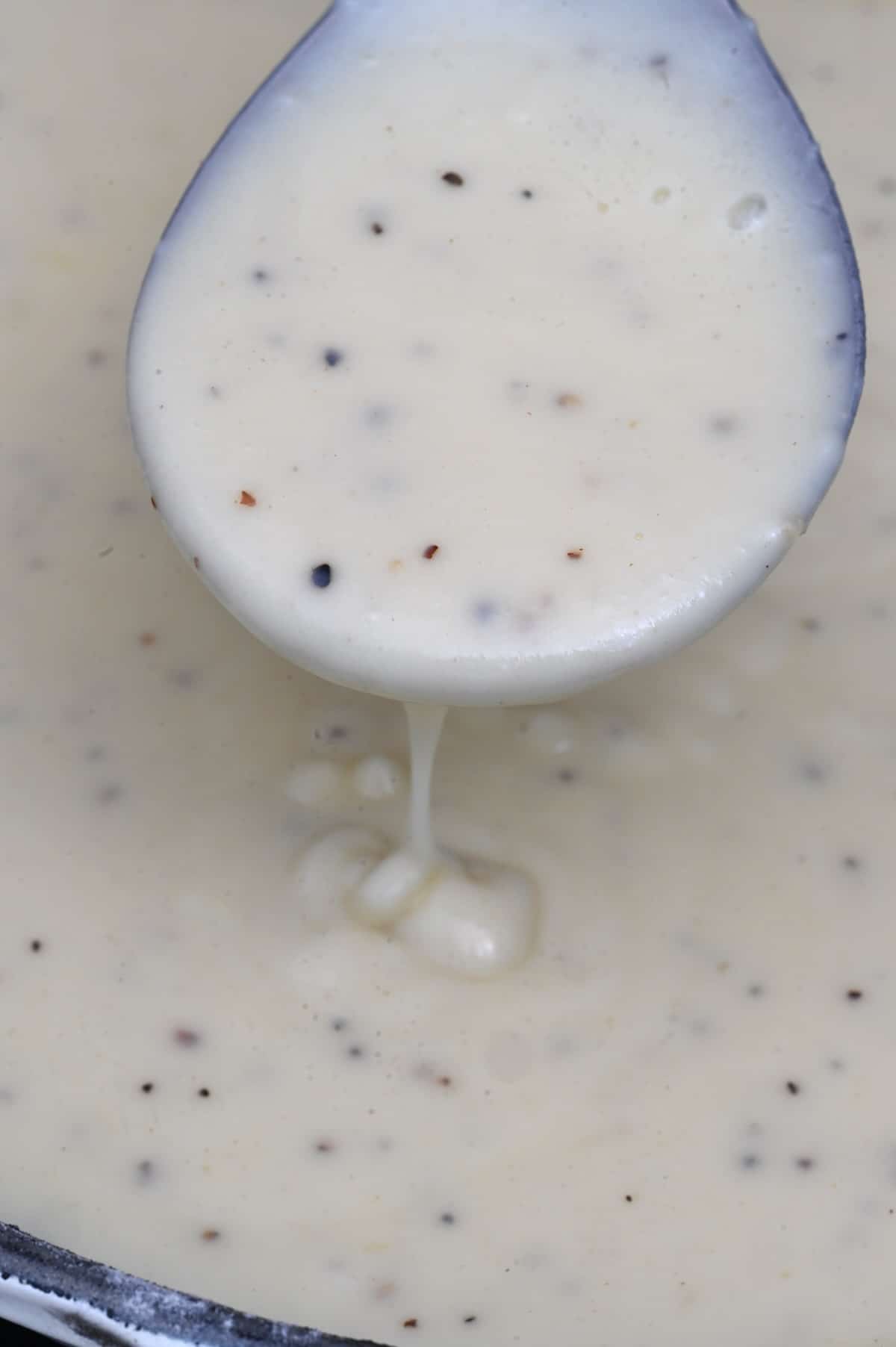 White gravy dripping from a spoon