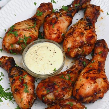 Chicken drumsticks with white sauce in a small bowl