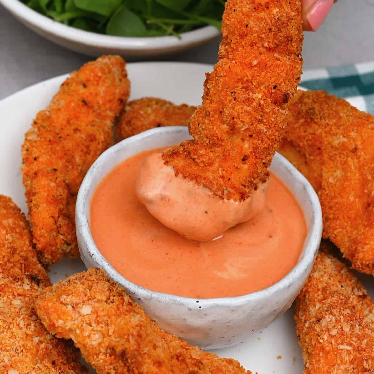 Dipping chicken tenders in cane's sauce