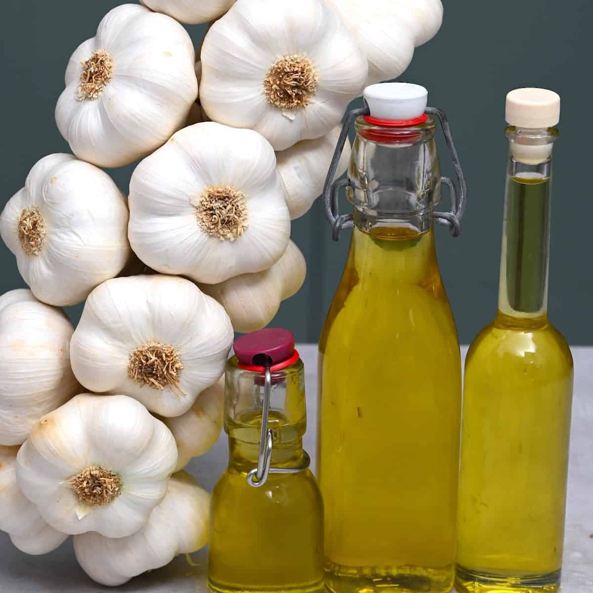 Garlic oil in small bottles and garlic heads next to them