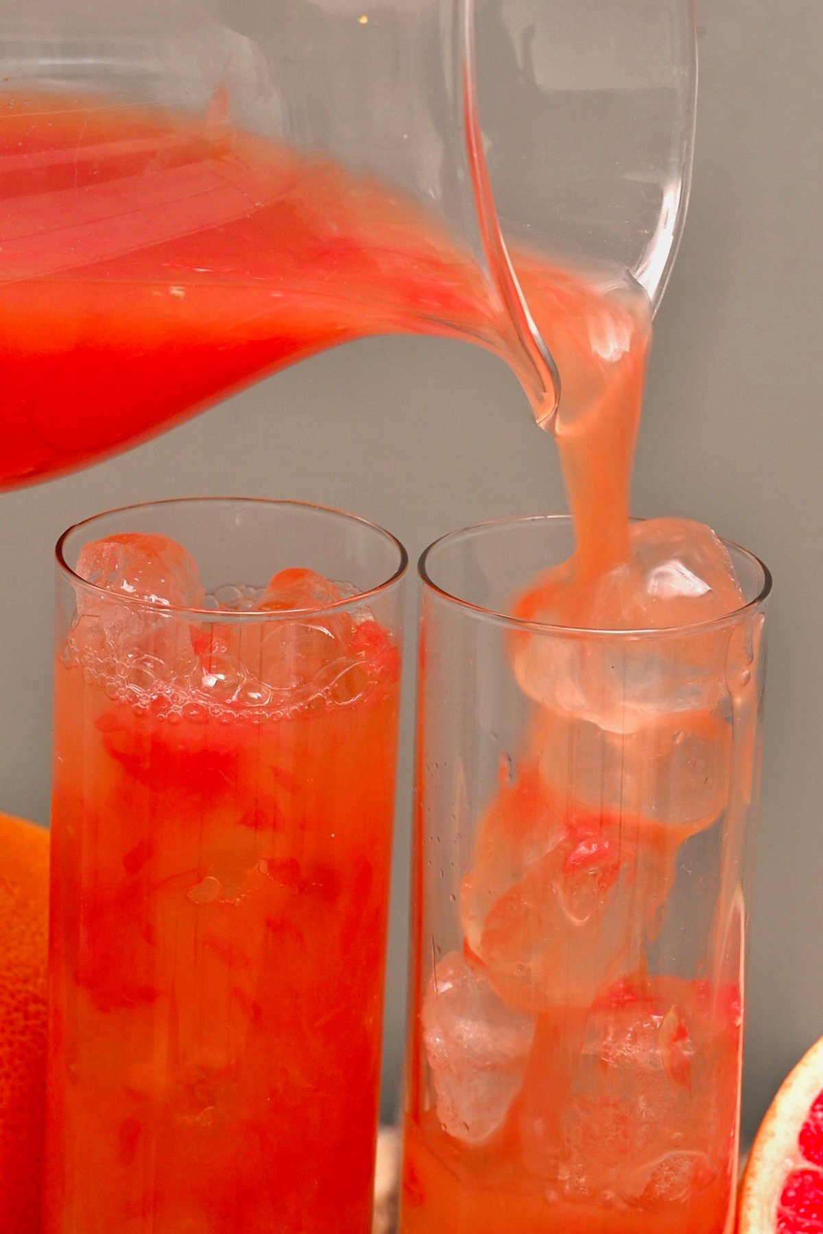 Pouring grapefruit juice into a glass with ice cubes