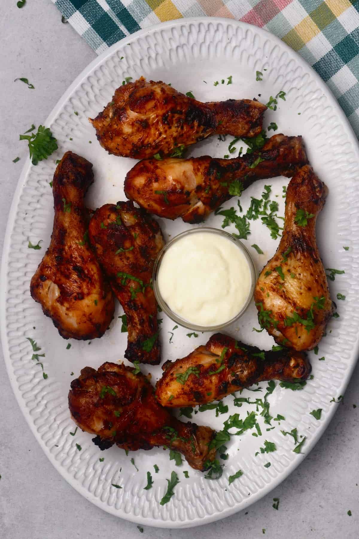 A small bowl of garlic aioli in the midst of chicken drumsticks
