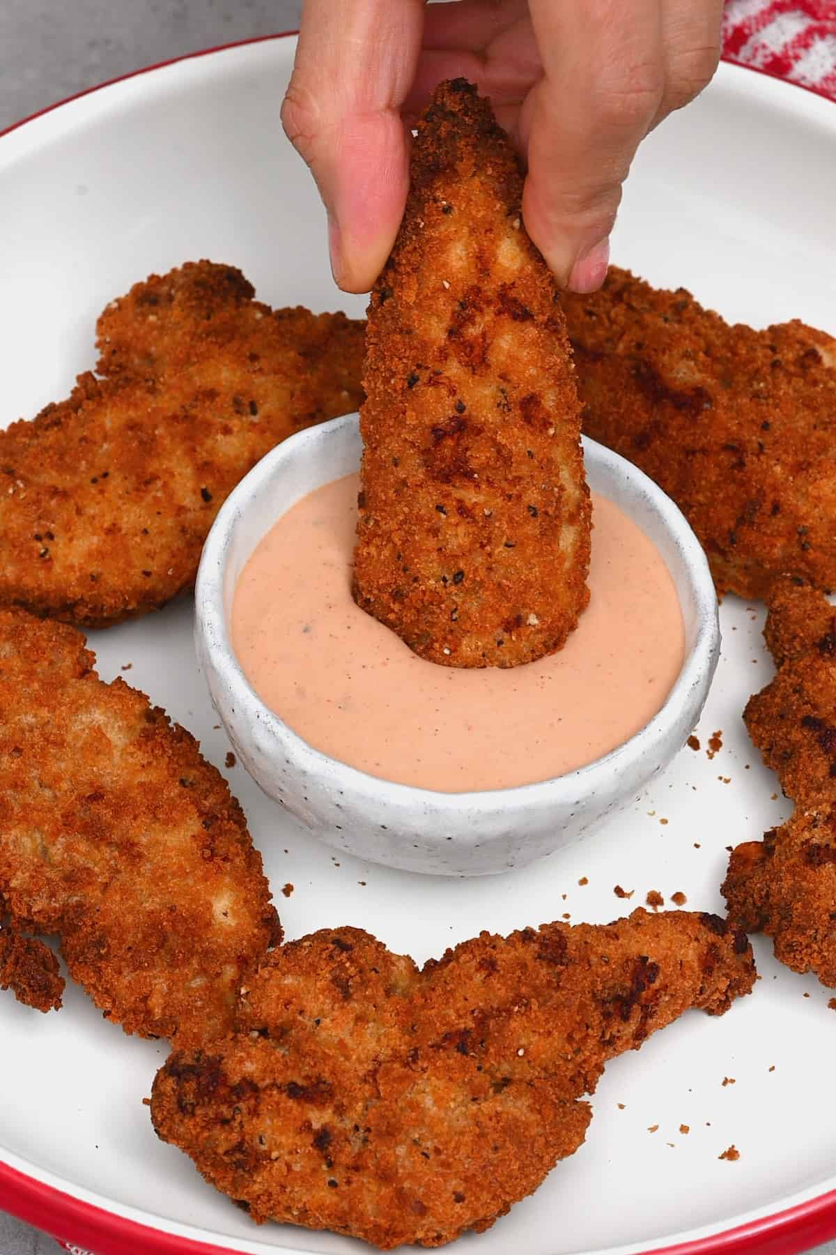 Dipping chicken tenders in Raising Cane's sauce