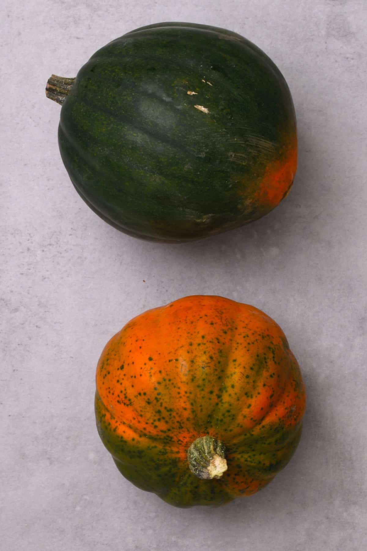 Two acorn squashes on a flat surface