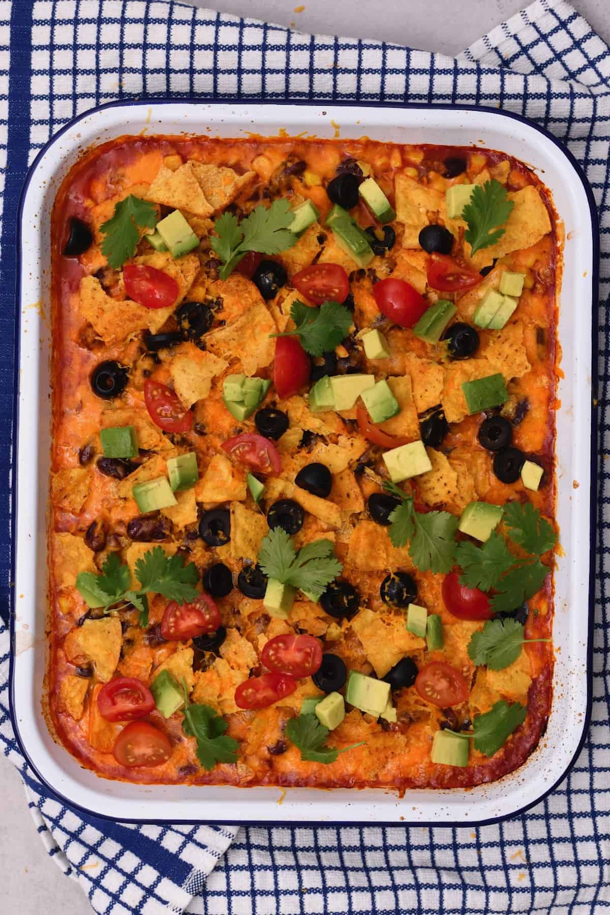Freshly baked taco casserole topped with avocado, tomatoes, and cilantro
