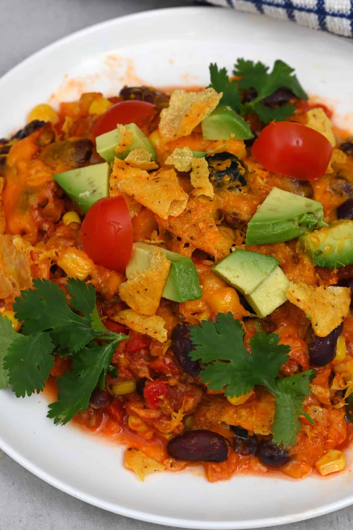 A serving of taco casserole topped with avocado, tomatoes, and cilantro