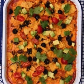 Freshly baked taco casserole topped with avocado, tomatoes, and cilantro