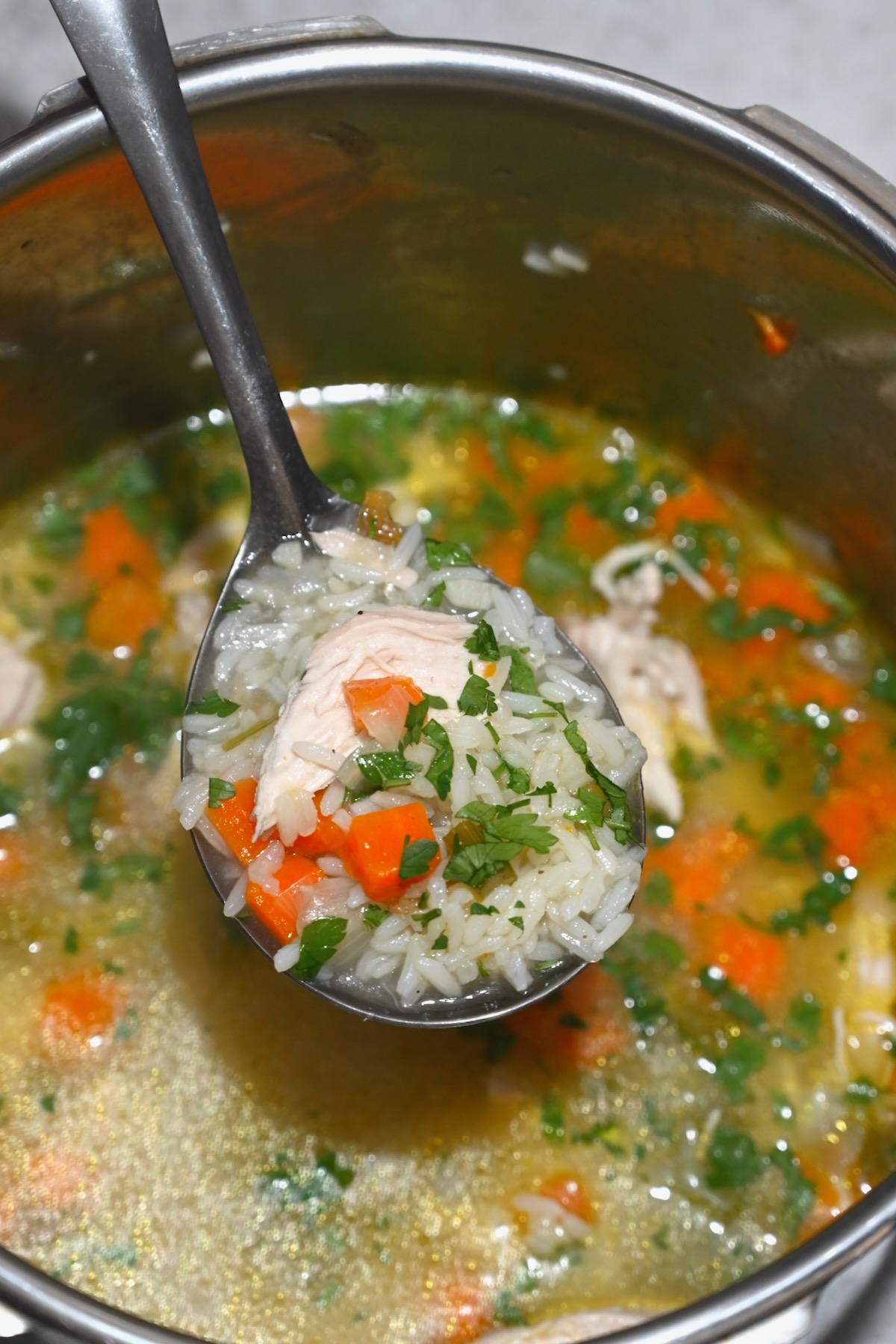 A ladle with freshly made chicken and rice soup