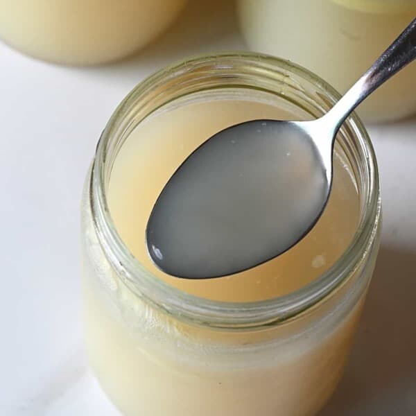 A spoonful of homemade chicken stock over a jar