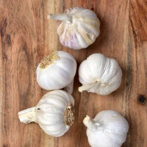 Five full heads of garlic on a chopping board