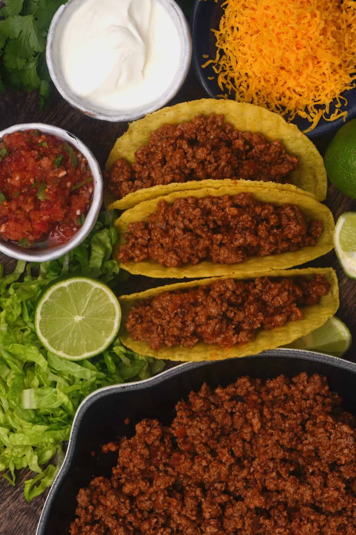 Assembling ground beef tacos with toppings