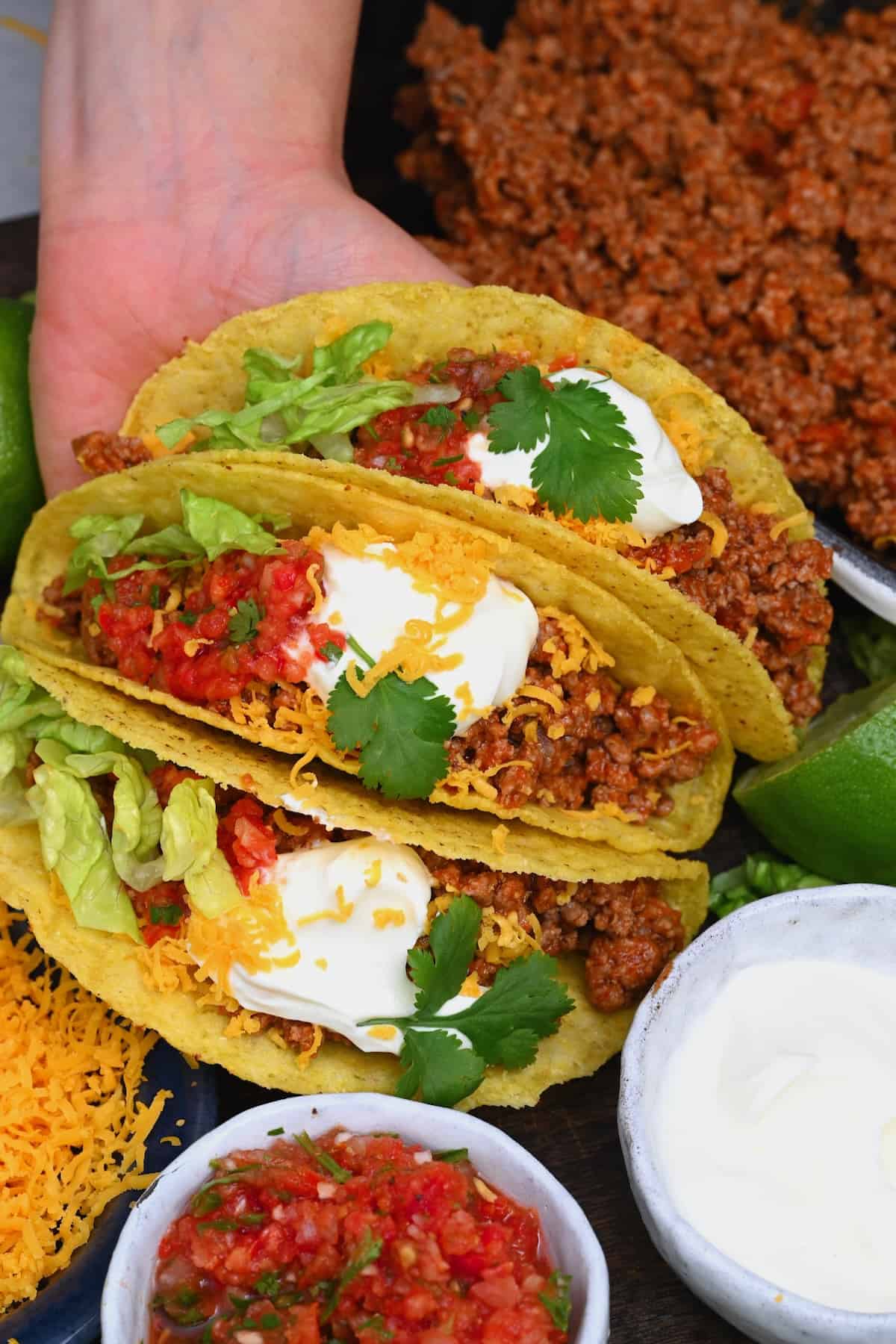 Ground beef tacos topped with sour cream and cheese