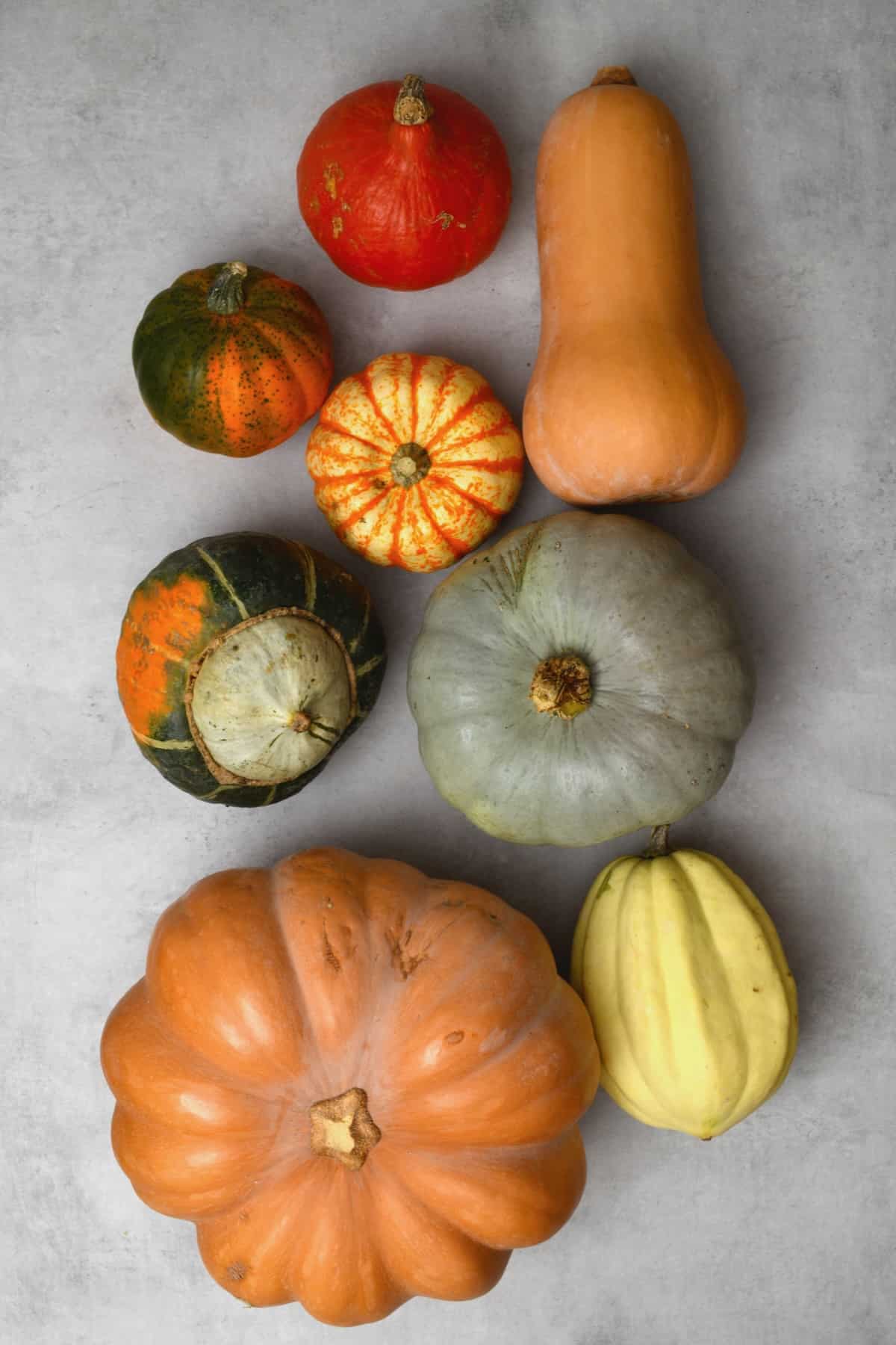 Different types of winter squash on a flat surface