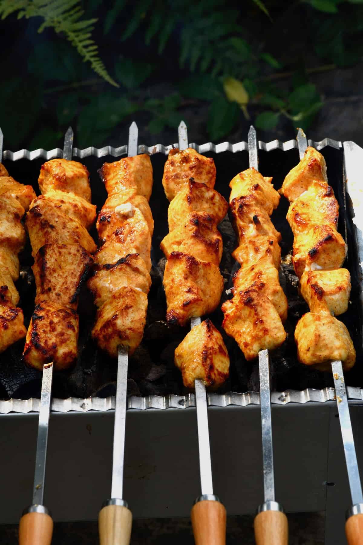 Shish tawook skewers cooking on a grill
