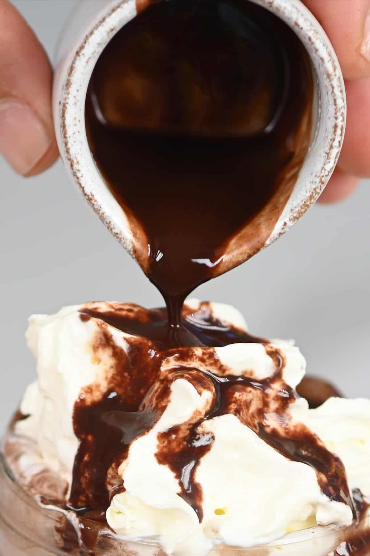 Pouring homemade chocolate syrup over a drink with whipped cream