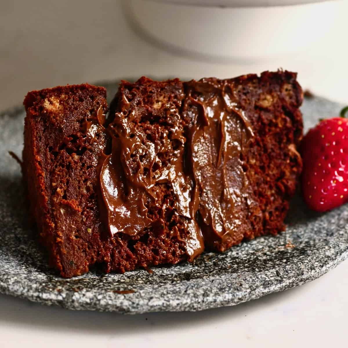 A slice of chocolate zucchini cake topped with a strawberry