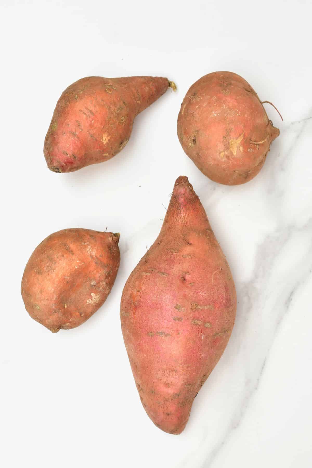 Four Sweet potatoes on a flat surface