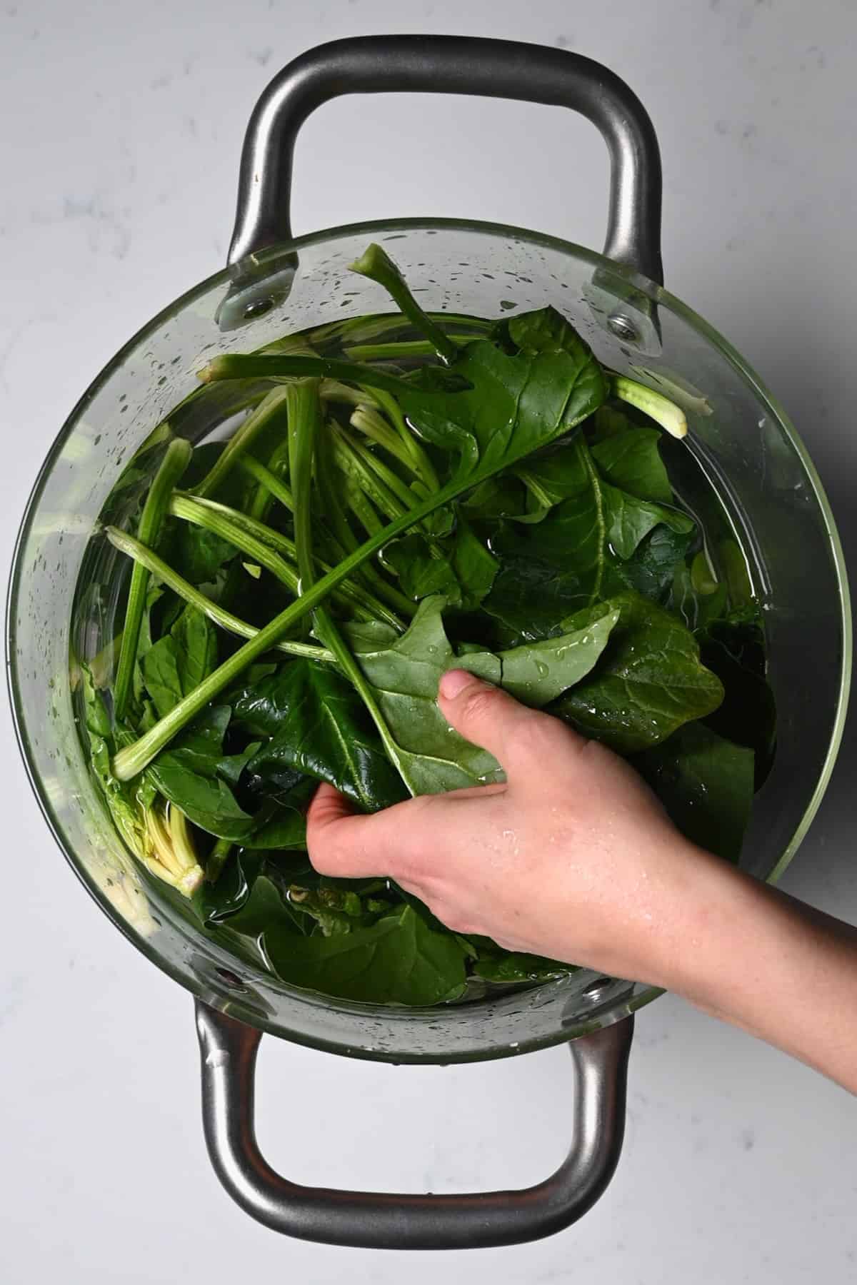 Washing spinach in a large bowl of water