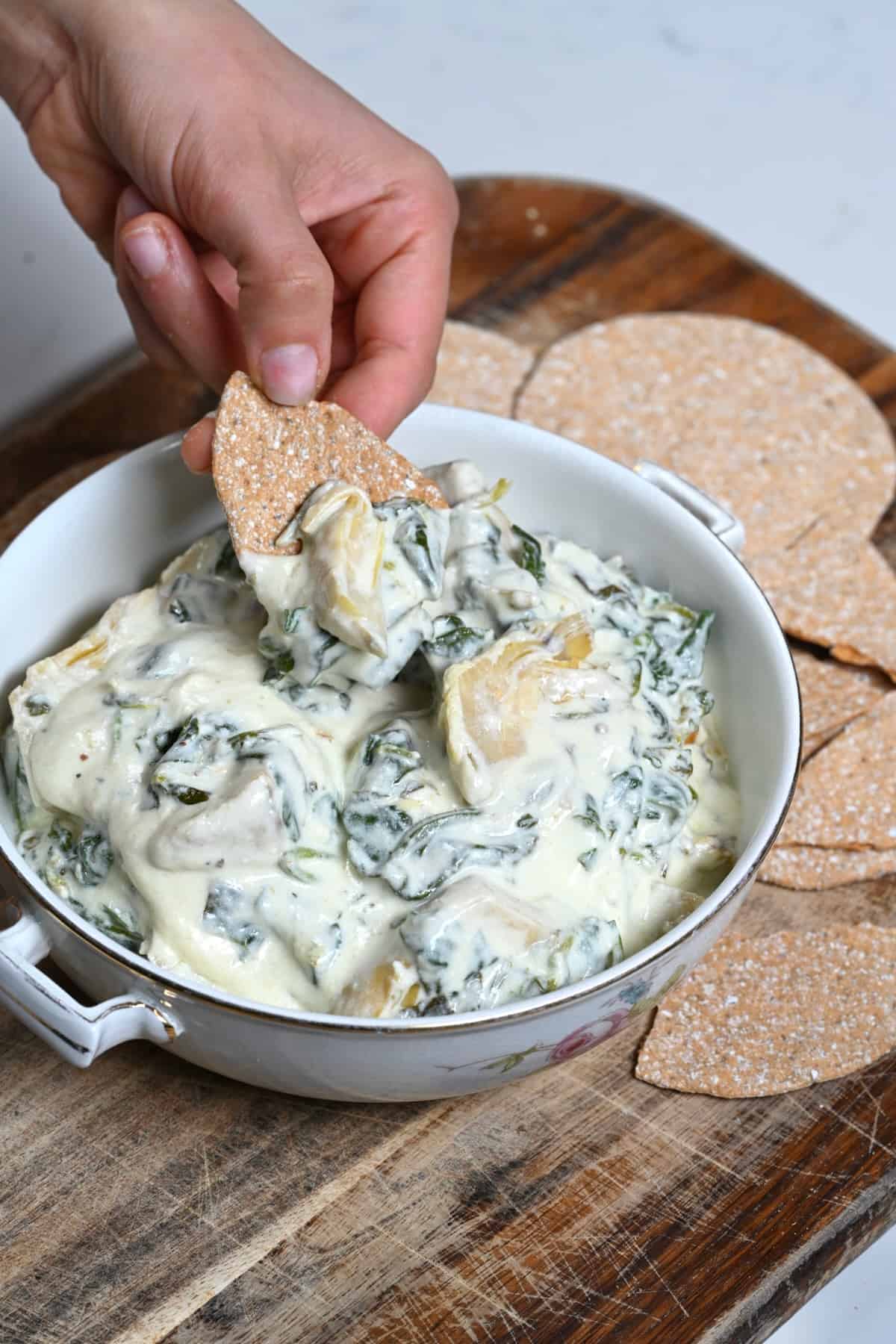 Dipping a chip into artichoke and spinach mix