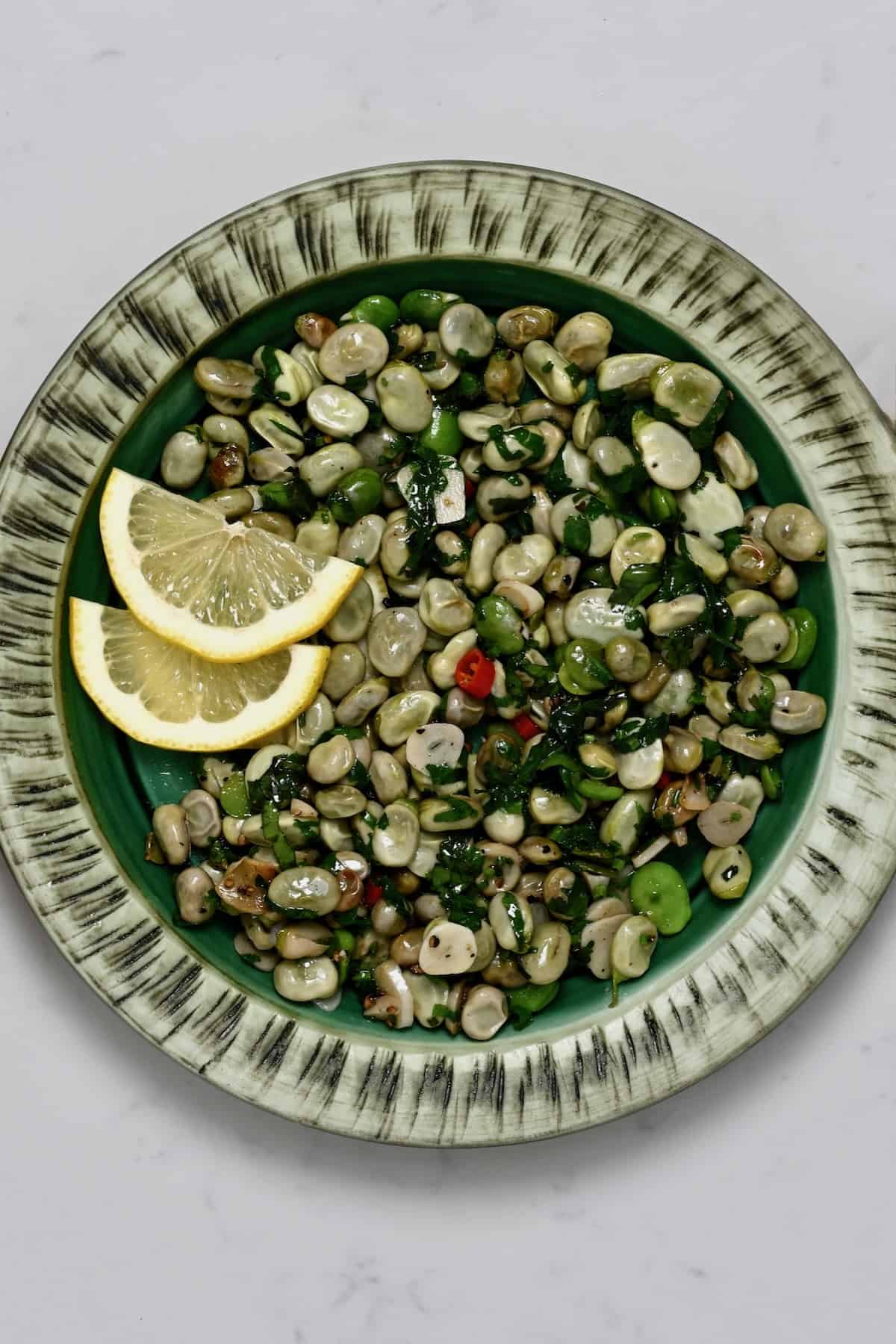 A serving of sauteed fava beans with lemon slices
