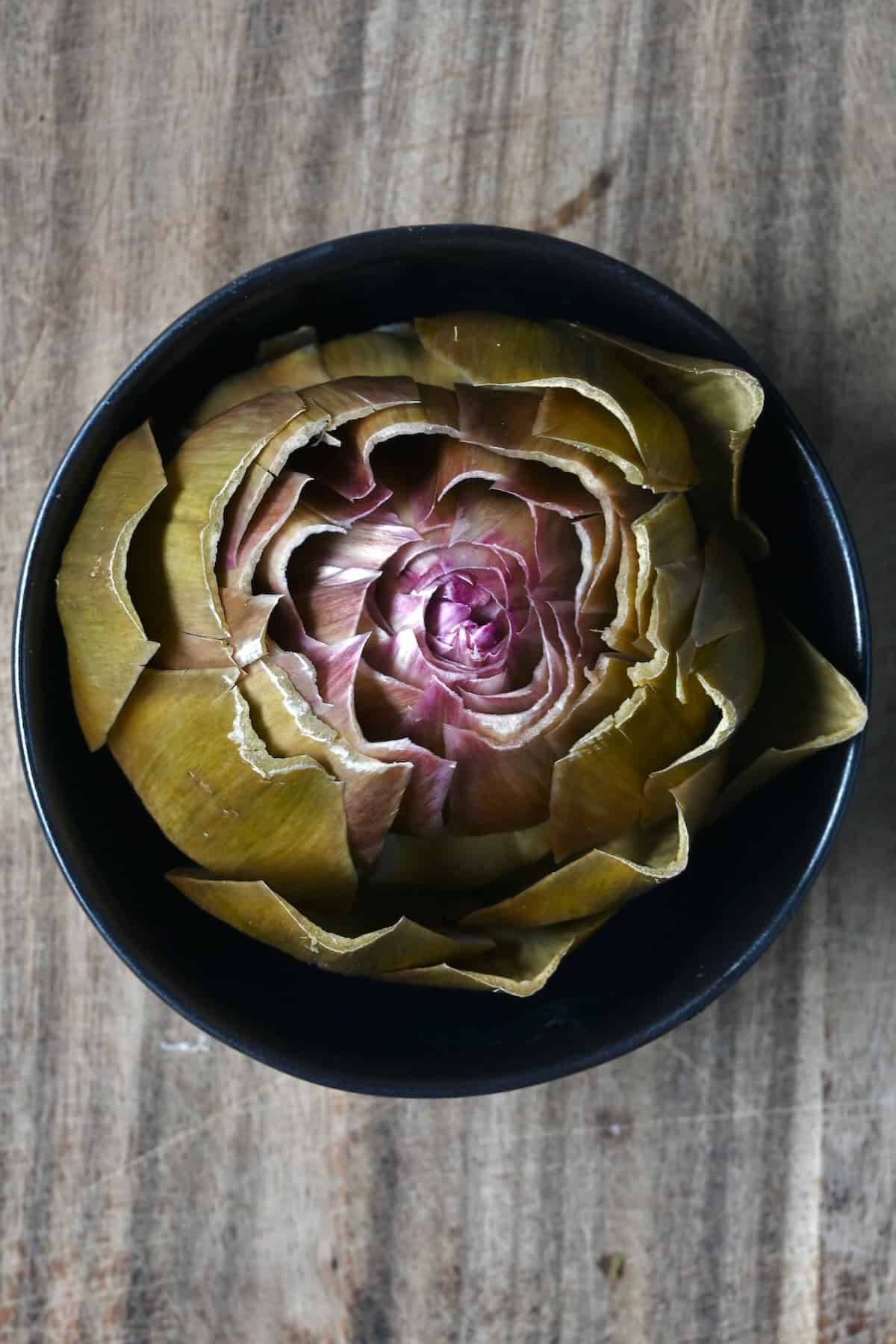 Steamed artichoke in a small bowl