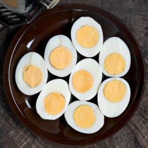 Four cooked eggs cut in half next to an instant pot