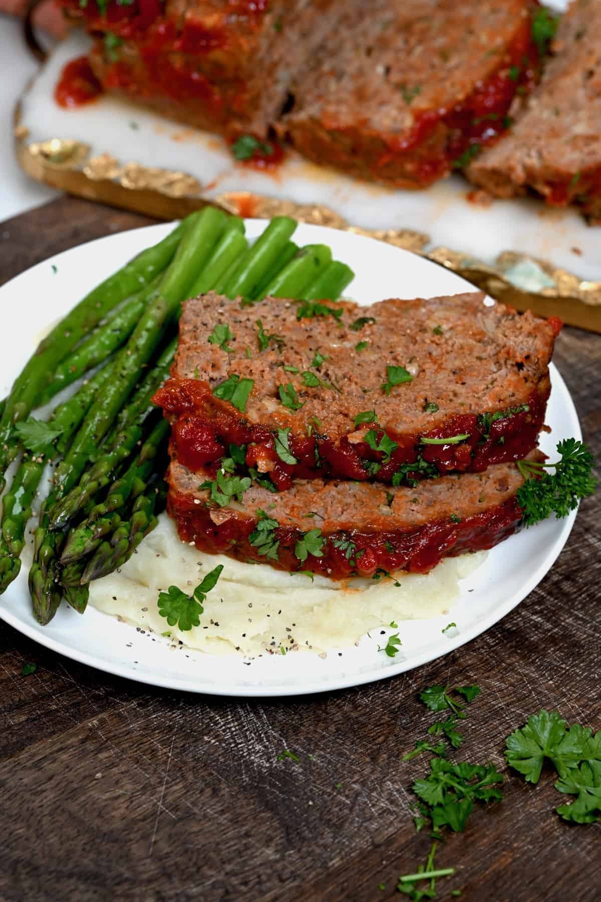 A serving of meatloaf with mashed potatoes and asparagus