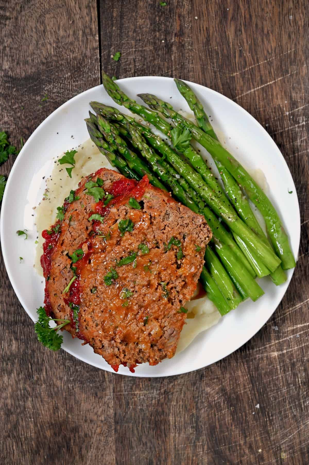 A serving of meatloaf with mashed potatoes and asparagus