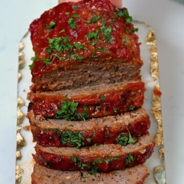 Glazed meatloaf cut into slices and topped with parsley