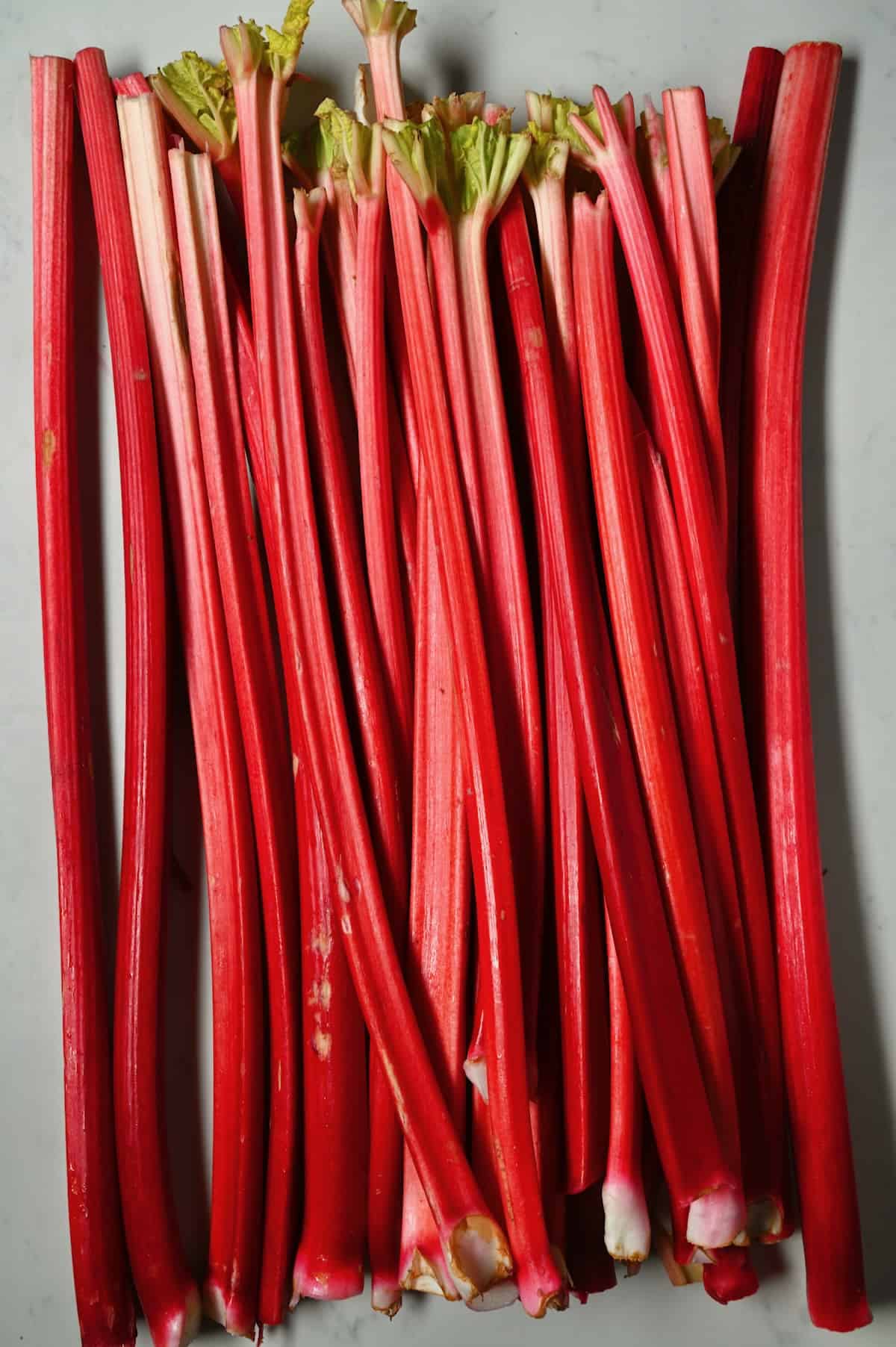 A bunch of rhubarb stalks on a flat surface