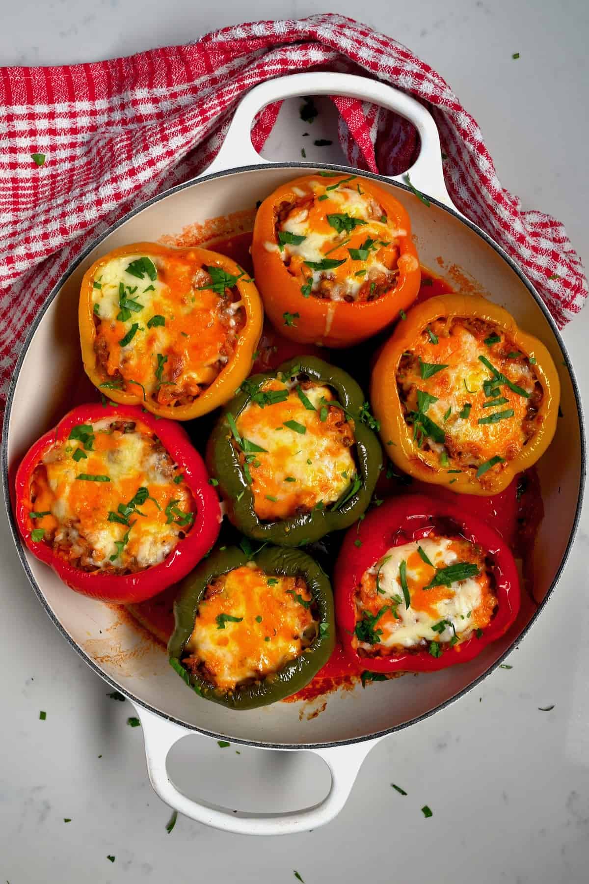 Seven stuffed bell peppers topped with melted cheese and parsley