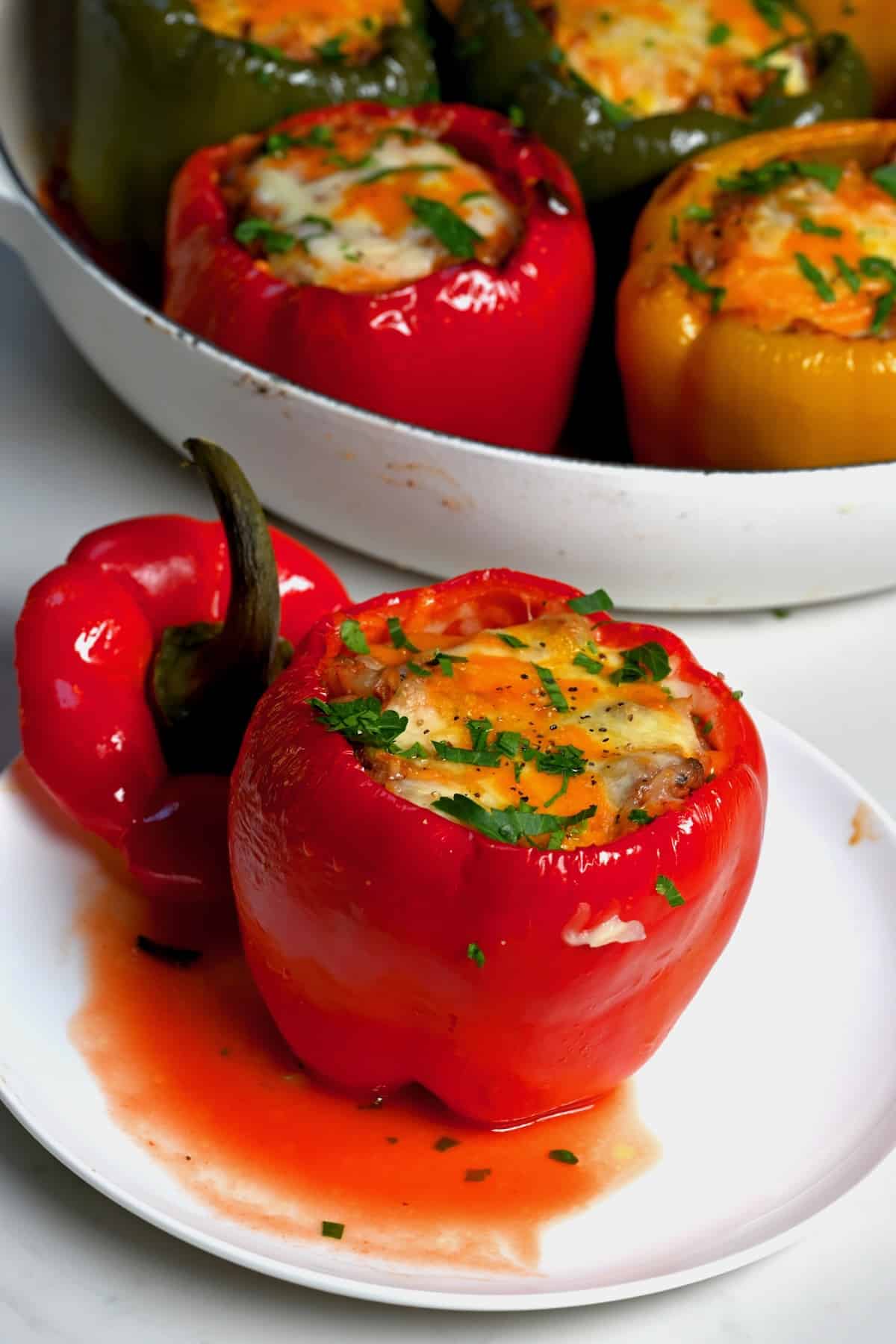 A serving of stuffed red bell pepper topped with melted cheese and parsley