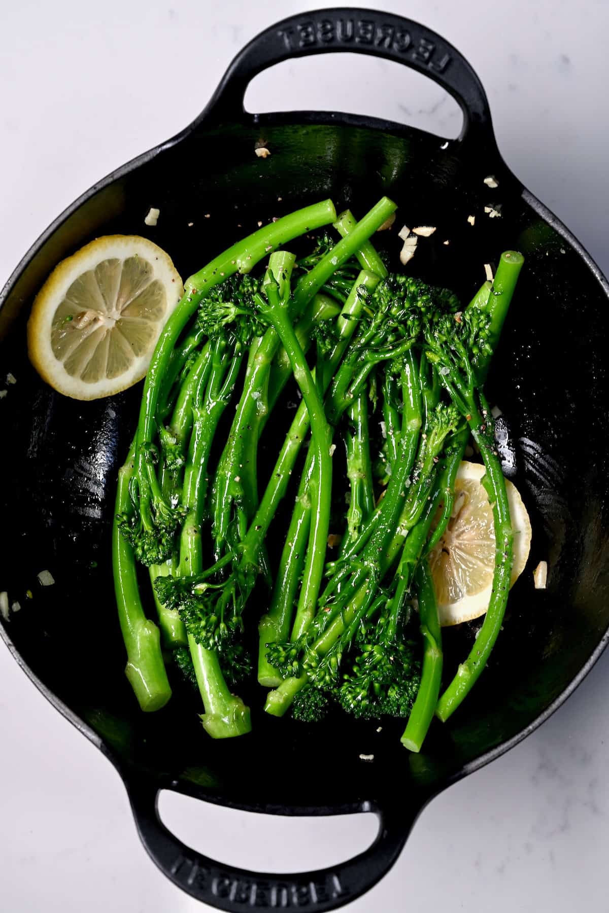 Sauteed broccolini in a pan with lemon slices