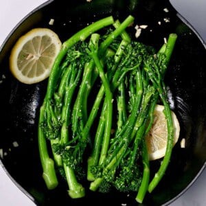 Sauteed broccolini in a pan with lemon slices