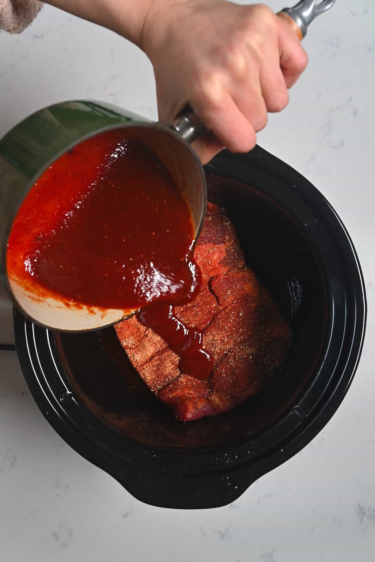 Pouring BBQ sauce over a brisket