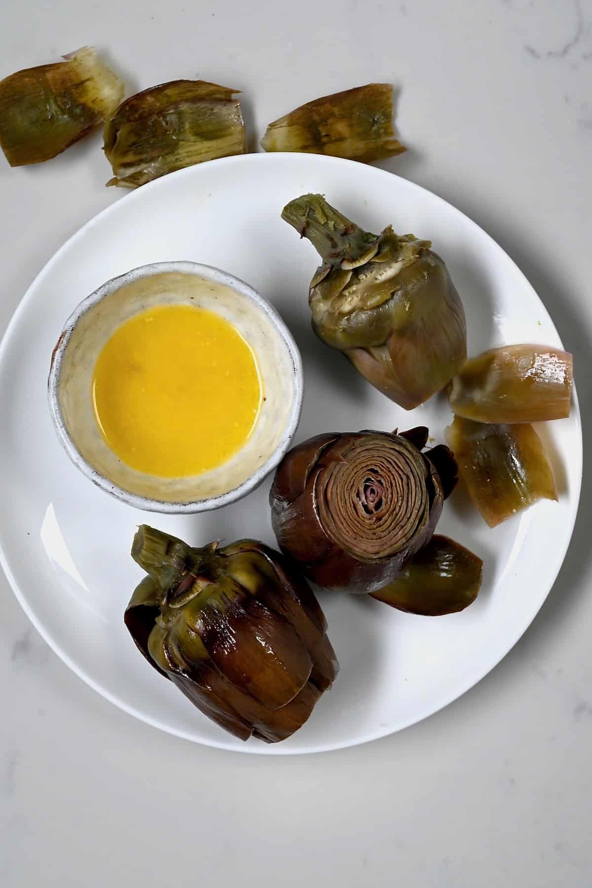 Cooked artichoke served with lemon butter sauce