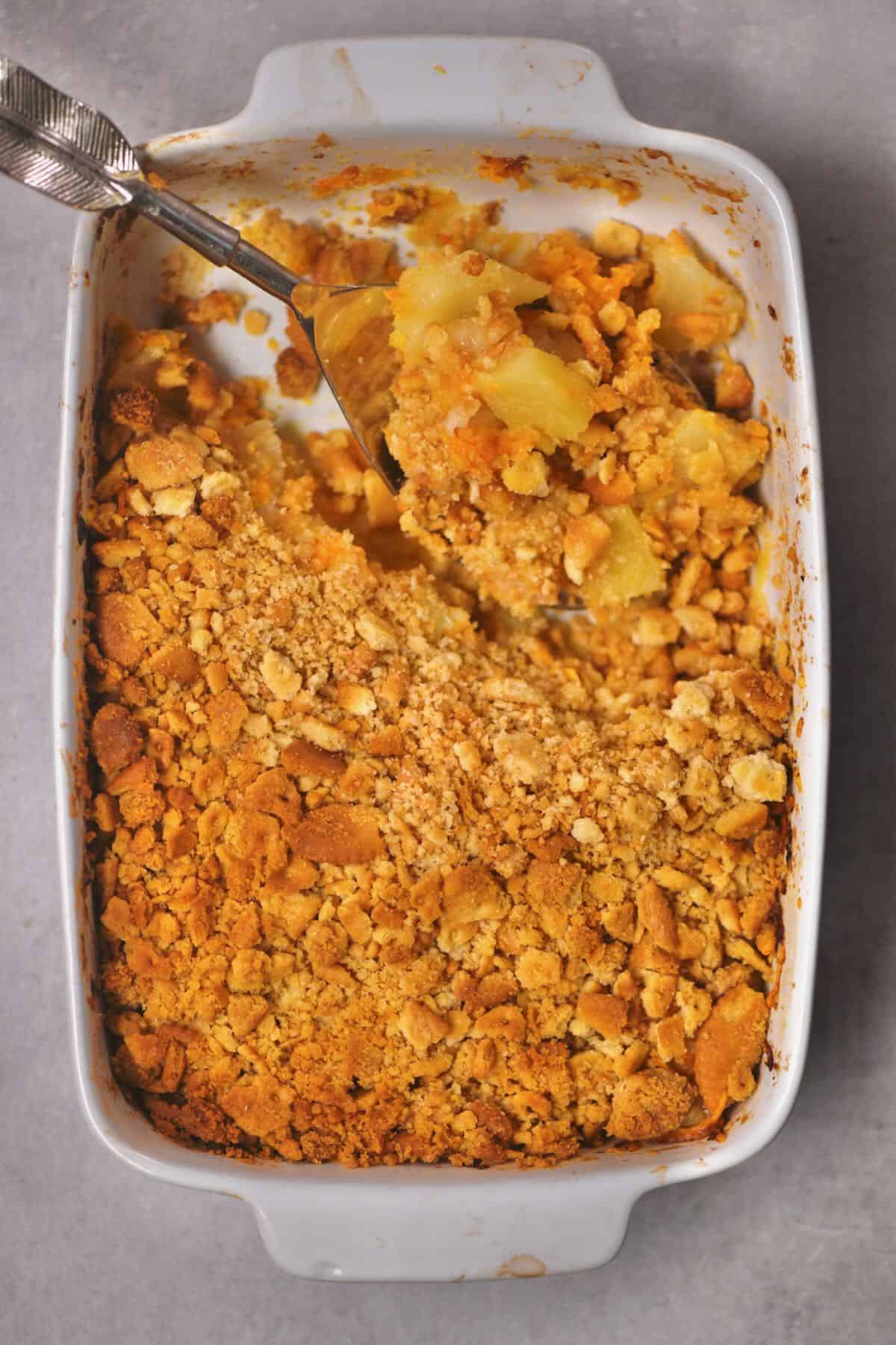 A spoonful of pineapple casserole over a baking dish