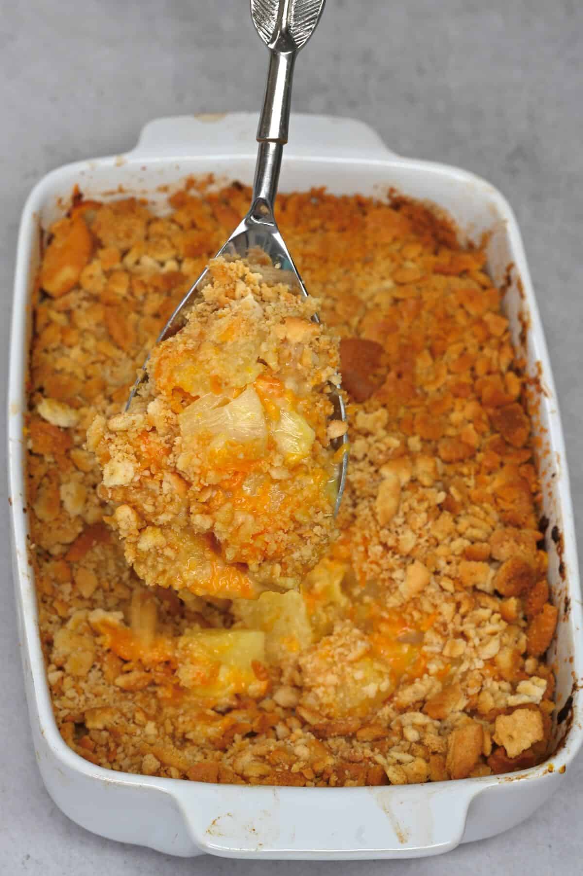 A spoonful of pineapple casserole over a baking dish