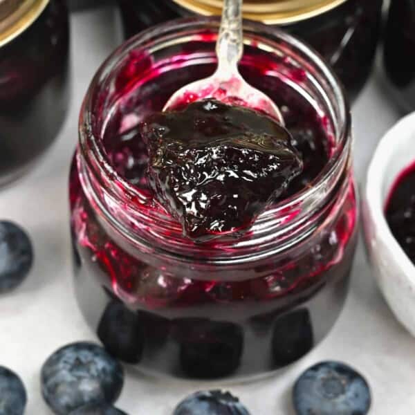 A spoonful of homemade blueberry jam over a small jar